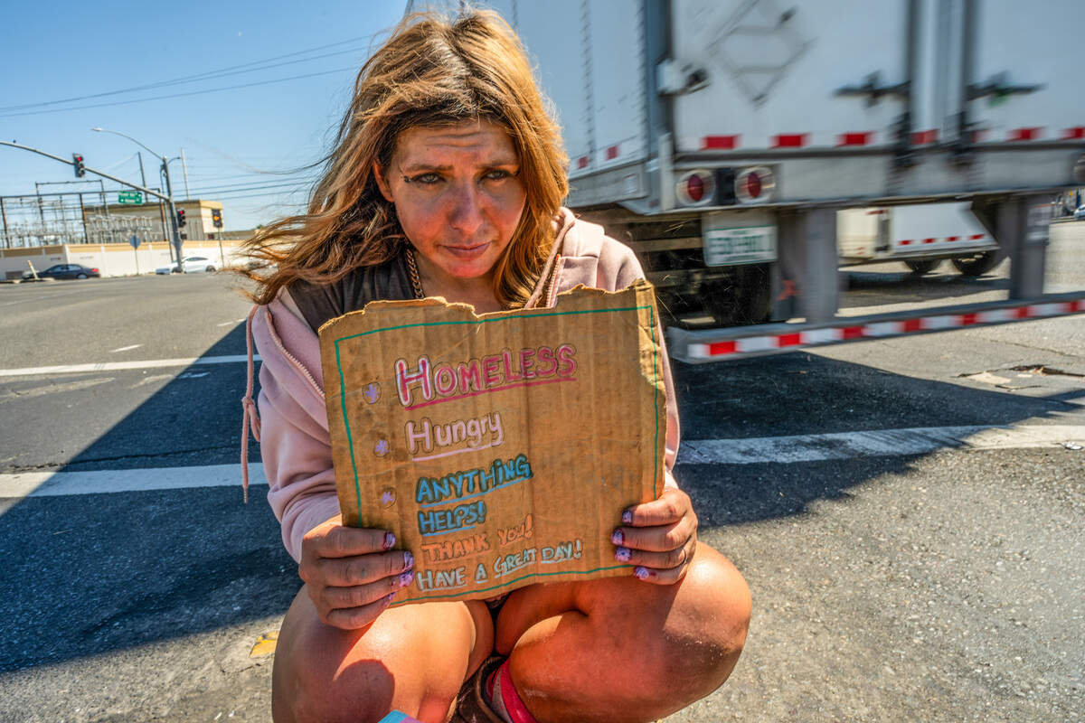 Califia Carlisle, 32, holds a sign that says “Homeless, Hungry, Anything helps!” as she balances in July on a slender median between traffic at the intersection of Howe Avenue and Folsom Boulevard in Sacramento.